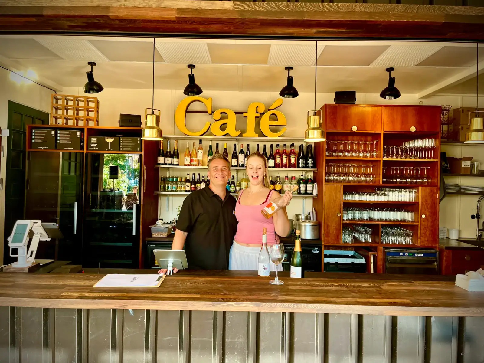 To medarbejdere står bag Havekaféens bar under det store Café-skilt.